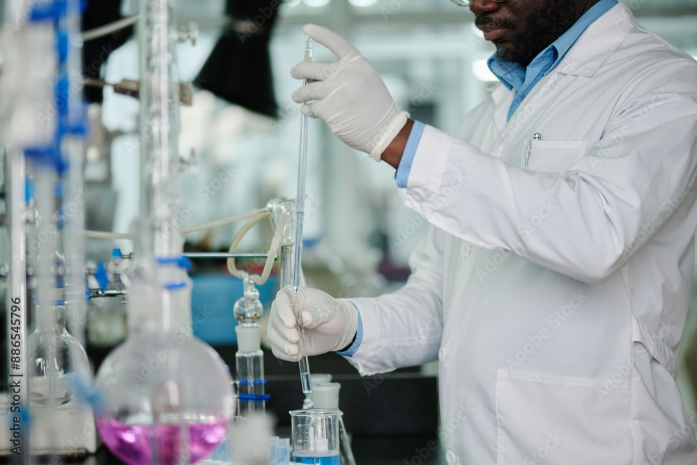 Poster cropped shot of modern male chemist in gloves and lab coat standing by workplace in laboratory and u