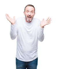 Fototapeta premium Middle age hoary senior man wearing white t-shirt over isolated background clueless and confused expression with arms and hands raised. Doubt concept.