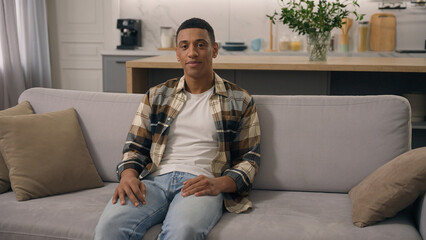 Obraz premium Portrait home glad good mood positive ethnicity man smiling looking at camera resting weekend at comfortable couch healthy African American ethnic guy male boyfriend smile toothy at sofa relax renter