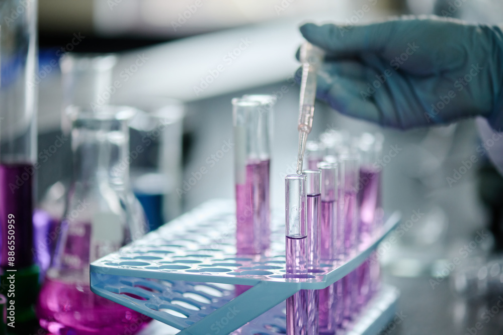 Poster Hand of gloved laboratory worker with pipette dropping transparent liquid into flask with purple substance during scientific experiment