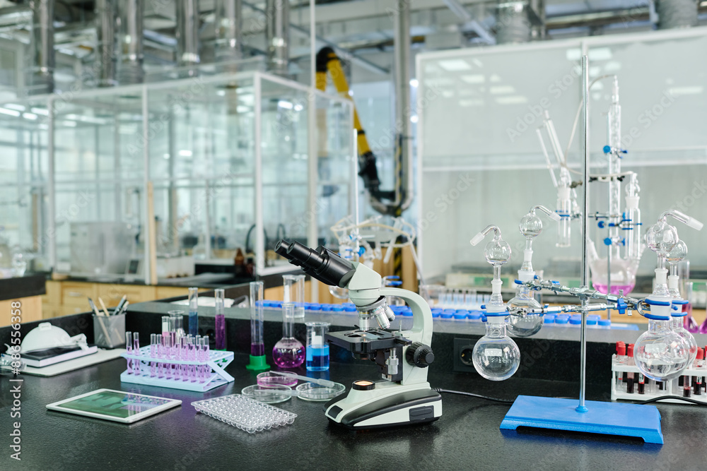Poster part of modern spacious laboratory with workplace of clinician or chemist with set of glassware, mic