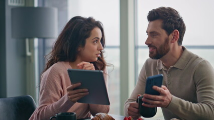 Happy lovers discussing tablet screen at weekend breakfast closeup. Man drinking