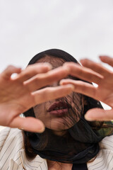 Fototapeta premium A young woman in white attire, her face covered by a veil, enjoying the summer breeze in a field of nature.