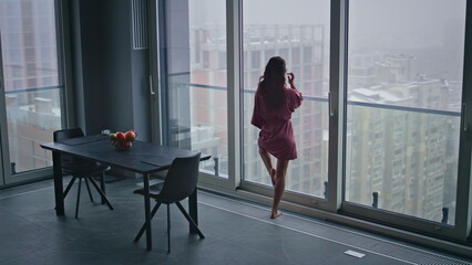 Obraz premium Morning model looking window modern kitchen back view. Domestic woman dreaming