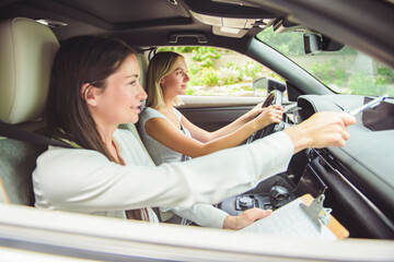 driver courses and people concept a car driving school instructor teaching young woman to drive