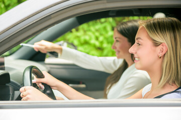 driver courses and people concept a car driving school instructor teaching young woman to drive