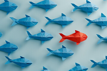 Origami fish in blue and red arranged on a light blue background, symbolizing uniqueness and individuality.