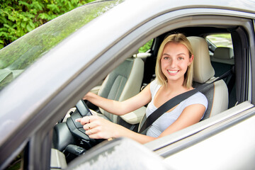 Naklejka premium Happy teen girl driver on car on summer day
