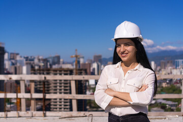 Portrait of a young woman in a white helmet at a construction site. Architecture, project management, civil engineering, building inspection.
