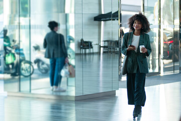 African businesswoman holding a coffee cup walking through a office hallway