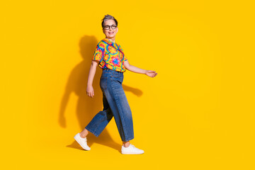 Fototapeta na wymiar Photo of positive lovely senior woman wear trendy print clothes going empty space isolated on vibrant yellow color background