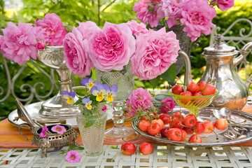 Roses and cherries still life on a table in a garden