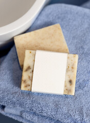 Soap bar with blank label on blue towels near vessel sink in bathroom closeup, mockup