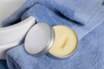 Opened body buttter jar on blue towels near basin in bathroom, cosmetic mockup