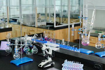 Various glassware, desktop computer and microscope standing on workplace of clinician or chemist in spacious modern laboratory