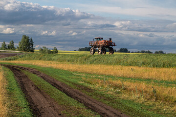 Fototapeta premium agricultural sprayer machine rolls along a rural road