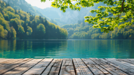 Scenic view of a tranquil lake surrounded by lush green forest and mountains, with a wooden deck in the foreground under a sunny sky.