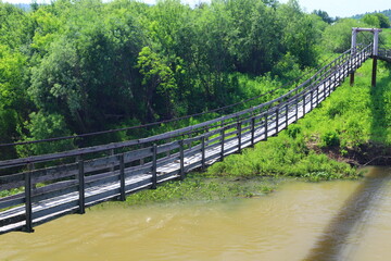 Fototapeta premium Old suspension bridge over the Suenga river in Maslyaninsky District of Novosibirsk Oblast. 