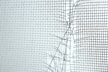 Torn window screen against white background, closeup
