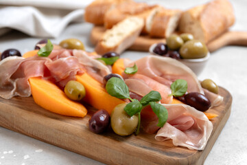 prosciutto or Parma ham or jamon serrano iberico with melon and olives traditional Italian appetizer antipasto 