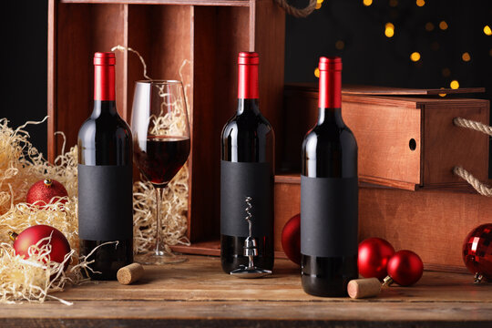 Bottles of wine, glass, wooden boxes, corks and red Christmas balls on table