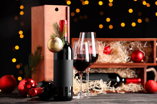 Bottles of wine, glasses, wooden boxes, fir twigs and Christmas balls on table