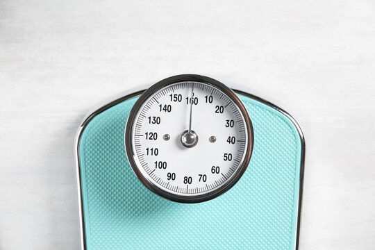 One bathroom scale on white wooden background, top view