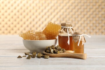 Natural honey tincture, propolis granules and sweet honeycombs on white wooden table