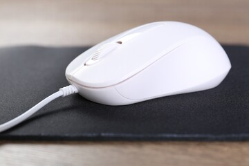 Computer mouse with mousepad on table, closeup