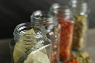 Different spices in glass jars on table, closeup