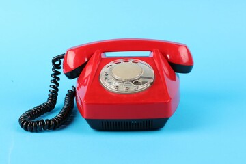Red telephone with handset on light blue background