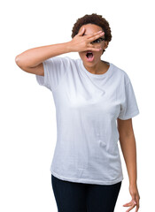 Beautiful young african american woman wearing glasses over isolated background peeking in shock covering face and eyes with hand, looking through fingers with embarrassed expression.