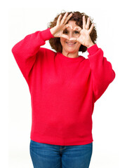 Beautiful middle ager senior woman red winter sweater over isolated background Doing heart shape with hand and fingers smiling looking through sign