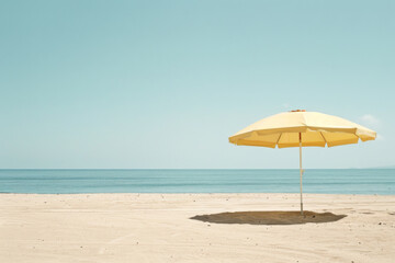 A lone yellow beach umbrella stands on an empty, sandy shore against a serene ocean backdrop