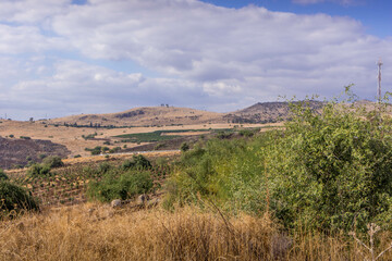 The hilly countryside in the area of Golan Heights, Galilee, with the Israeli settlements, farms, and grassy landscape.
