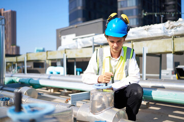 Technician checking pipeline valves or water tank area at urban industrial site