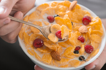 Man eating tasty cornflakes with milk in bowl, closeup