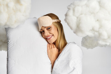 A dreamy blonde woman in cozy pyjamas holds a pillow, surrounded by fluffy clouds.