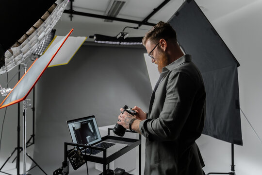 A professional photographer is reviewing camera shots in a modern studio setting