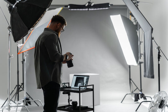 A photographer in a studio focuses on adjusting camera settings for the perfect shot