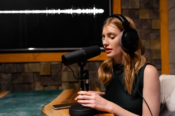 A woman is recording a podcast in a professional studio using a quality microphone