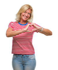 Middle age blonde woman over isolated background smiling in love showing heart symbol and shape with hands. Romantic concept.