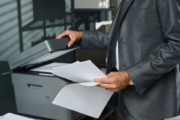 Unrecognizable mature male director of business company in formal suit holding paper documents...