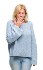 Middle age blonde woman wearing winter sweater over isolated background bored yawning tired covering mouth with hand. Restless and sleepiness.