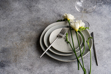 White Freesias on a stack of assorted ceramic plates next to a champagne coupe