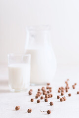 Milk in a glass and chocolate balls on a light background.