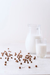 Milk in a glass and chocolate balls on a light background.