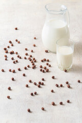 Milk in a glass and chocolate balls on a light background.