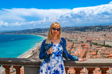 A woman enjoys a coastal city view on a sunny day, embracing the beauty and leisure of the moment. Nice, France.