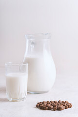 Milk in a glass and chocolate balls on a light background.